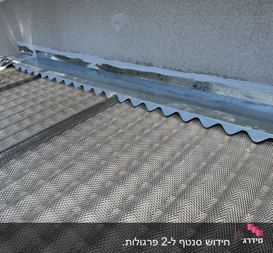 גג מתכת עם רשת מגן ליד קיר